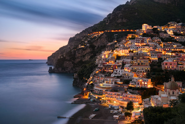 View of the picturesque Amalfi Coast in Campania, Italy, with the bright blue waters of the Tyrrhenian Sea, steep cliffs, colorful buildings, and boats docked at the shore